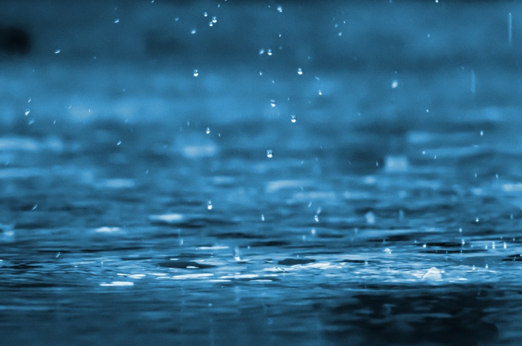 Regentropfen fallen auf eine Wasseroberfläche