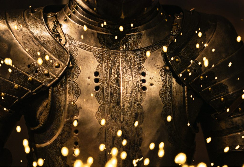 Die Brust einer Ritterrüstung. Davor springen glühende Funken empor.